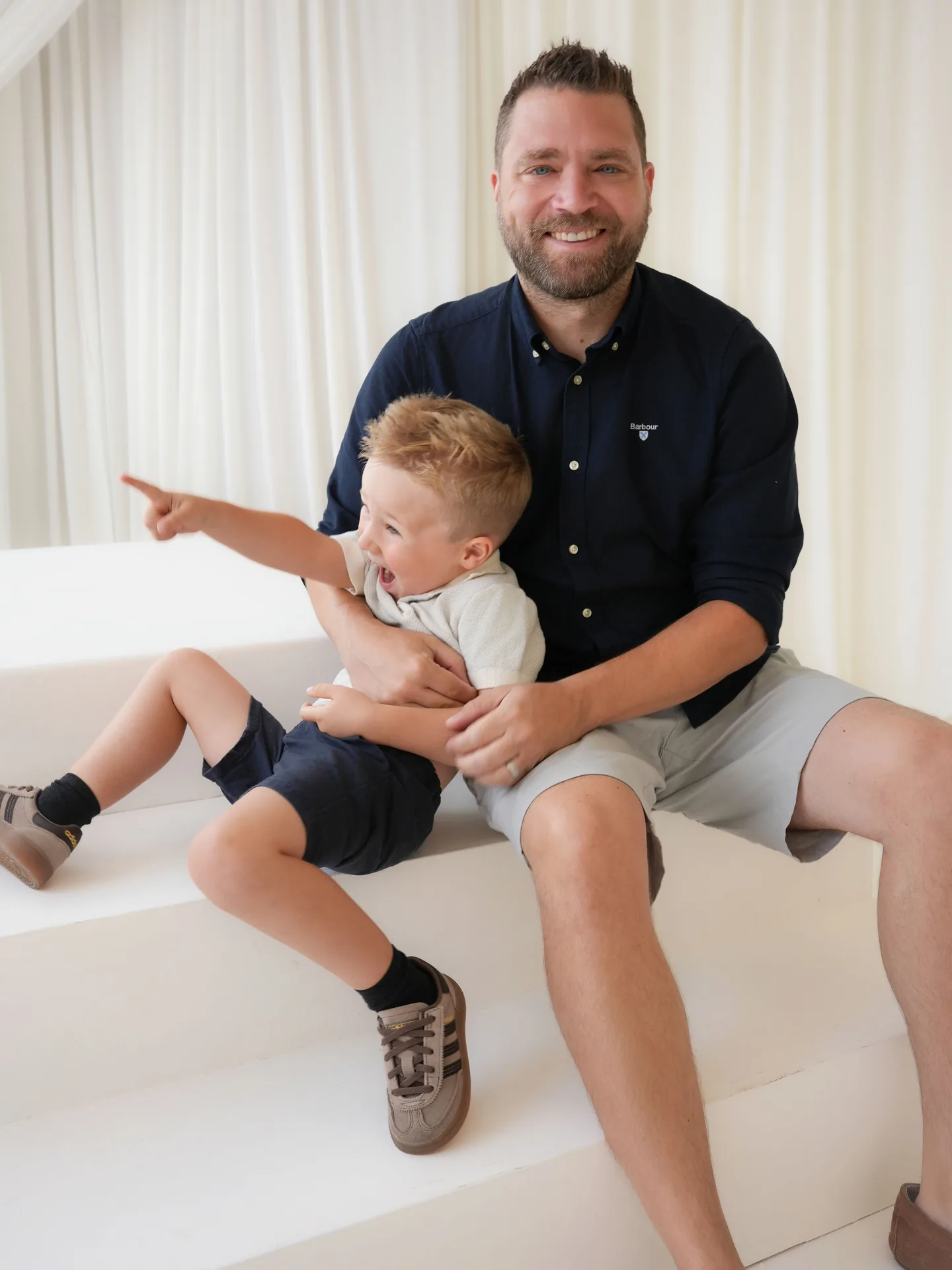 Father sitting with his two young sons on white studio steps